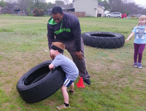 Robin Johnson teaching kids to flip tires at Conquer Fitness
